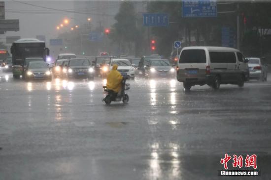 资料图:降雨天气中一名市民穿着雨衣骑车出行。<a target='_blank' href='http://www.chinanews.com/'>中新社</a>记者 贾天勇 摄