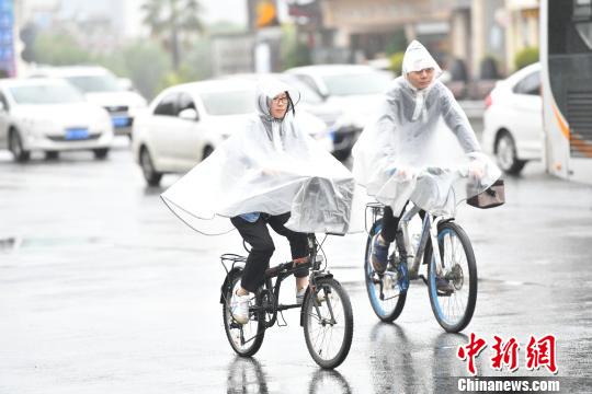 资料图:民众在雨中出行。张浪 摄