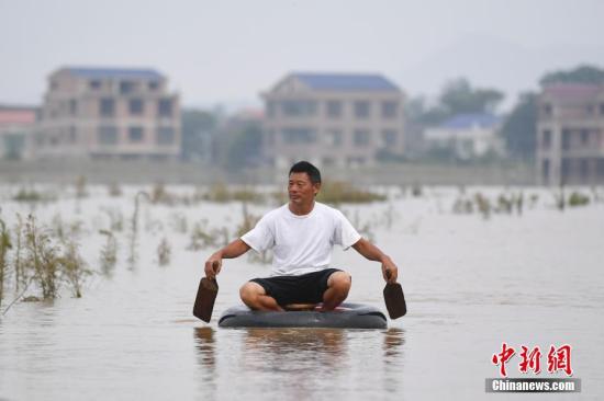 资料图:湖南衡东县出现持续强降雨天气,衡东县霞流镇洣河村洣水河堤发生两处漫堤决口。图为龙头村村民划着轮胎返回岸边。杨华峰 摄