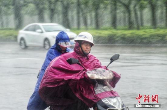 图为民众冒雨出行。 翟李强 摄