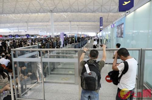 兩名旅客無奈地望着離境通道。圖片來源:香港大公文匯全媒體記者李斯哲攝