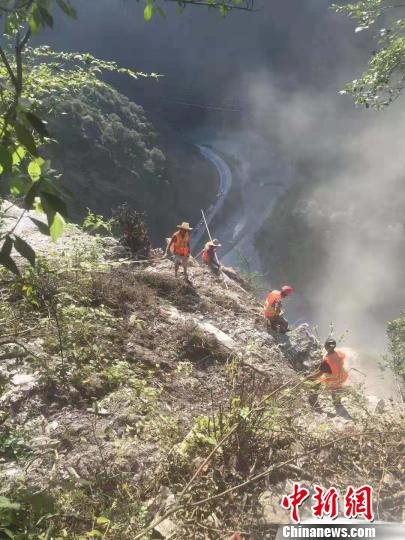 排危人员从山顶下到悬崖上清除危石。 北川宣传部 摄