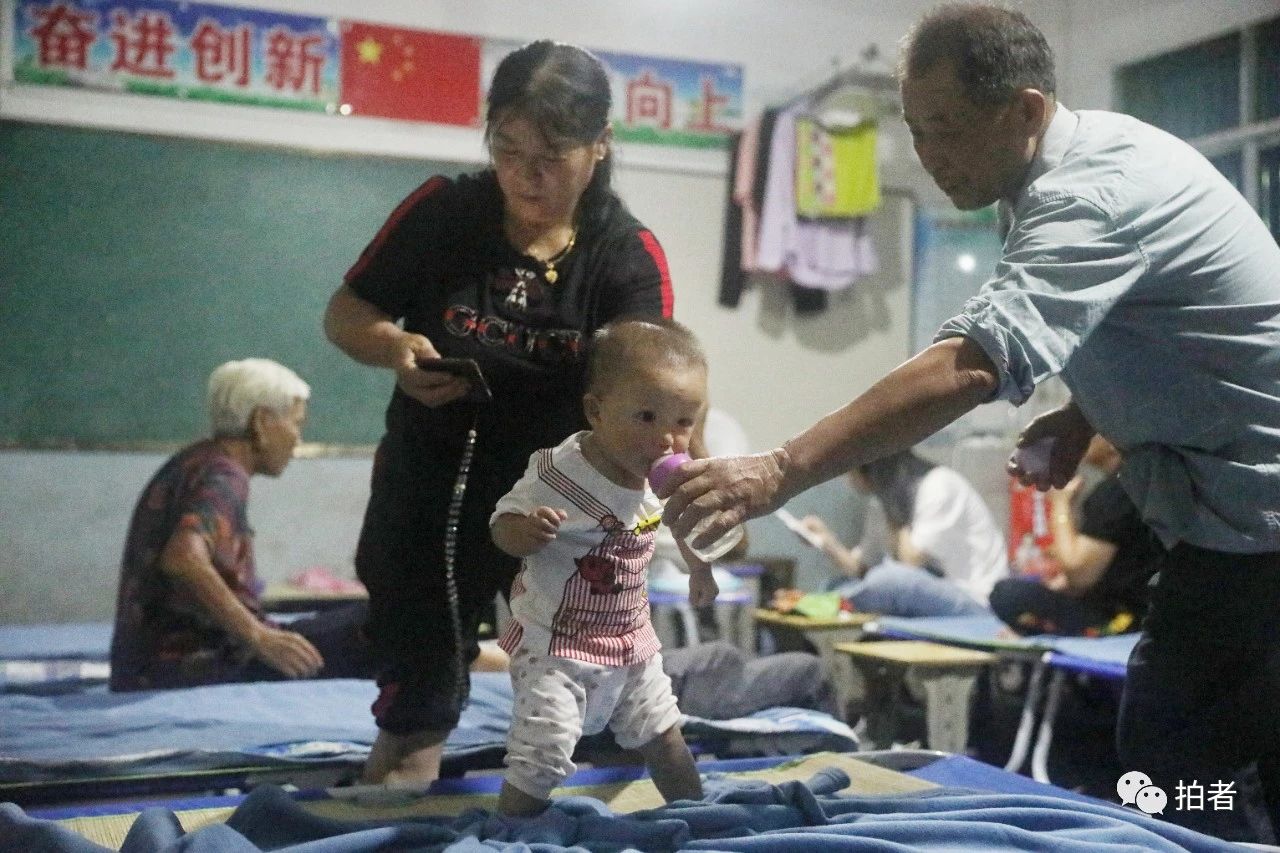 △ 7月10日晚,鄱陽縣油墩街鎮橋頭中心小學安置點,村民黃先生給小孫子喂水。