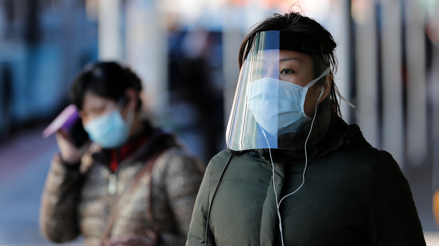 圖爲4月6日,紐約法拉盛華人社區,一名女性頭戴防護面罩行走在街頭。(圖片來源:中新社)