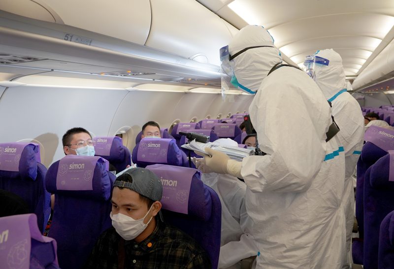 登臨檢疫組工作人員進入機艙覈實入境旅客信息。(圖片來源:中新社)