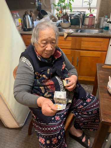 葉老太從錢夾掏出一百美金。(受訪者供圖)