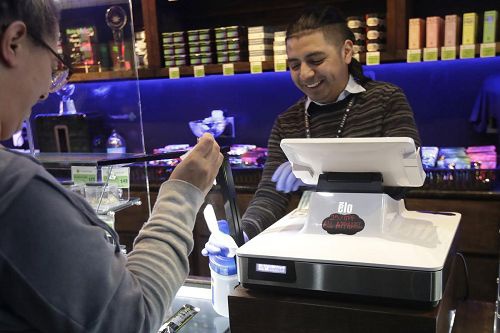 大麻商店内的员工将消费者会触碰到的物品消毒
