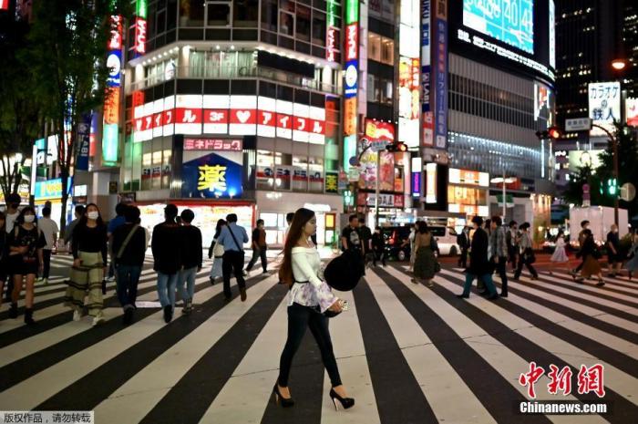 当地时间5月25日,行人穿过东京新宿区的一条街道。