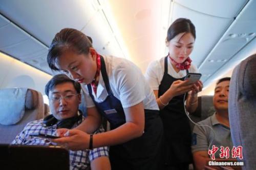 资料图:乘务员们在客舱内为旅客调试机上上网功能。<a target='_blank' href='http://www.chinanews.com/'>中新社</a>记者 殷立勤 摄