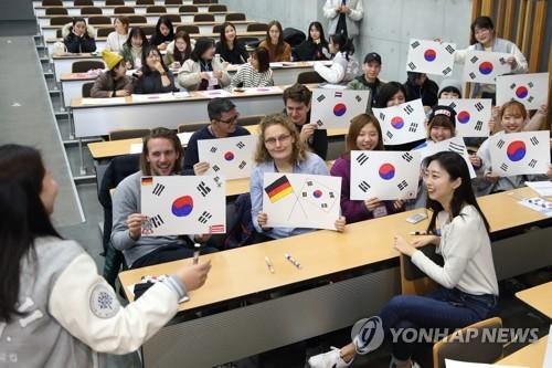 资料图片:2月27日,在首尔明知大学人文校区,外国人留学生手绘韩国国旗。(图片来源:韩联社,明知大学供图)